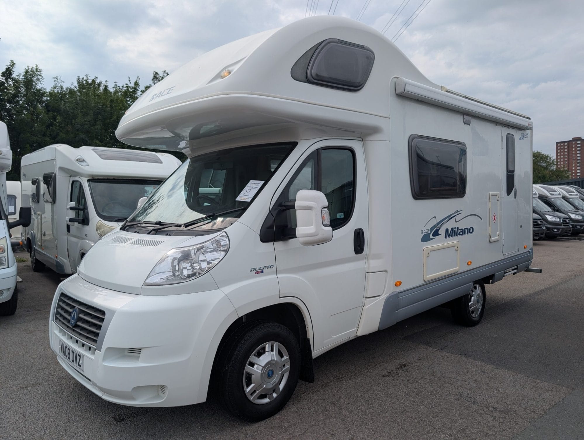 White Campervan with blue text decals. Over-cab shaping suggests rooftop bedroom